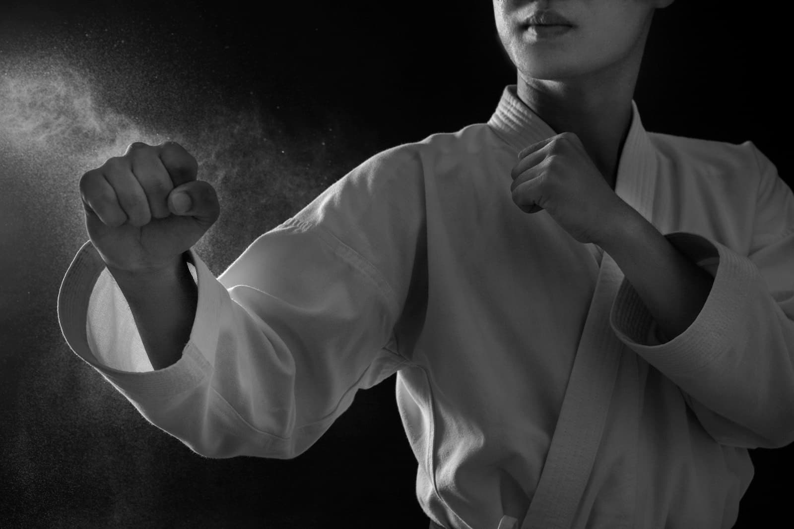 A karateka in a white gi holding a close guard, both fists up.